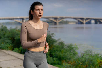 close up on the street on the river embankment in the city center on concrete path a sporty girl in a gray sports suit healthy lifestyle morning jogging imperfect figure