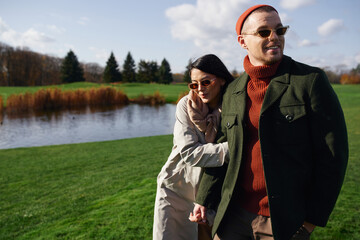 A couple enjoys a warm embrace by a serene lakeside in a beautiful autumn landscape.