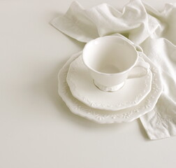 White ceramic coffee cup , sausers set  and white napkin isolated on white background. Elegant classic porcelain utensils.Copy space . Business food brand template.