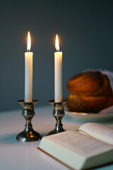 vertical photo Shabbat or Sabbath kiddush ceremony composition with a traditional sweet fresh loaf of challah bread, glass of red kosher wine and candles on a vintage wood table with copy space