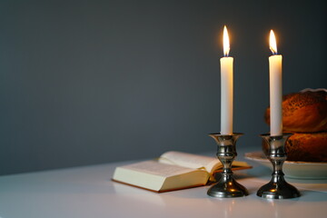 Traditional challah bread with wine and glowing candles on dark background. Shabbat Shalom