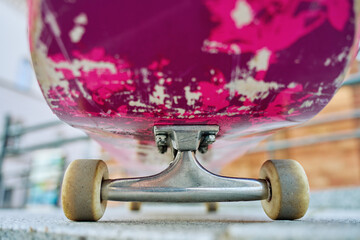Used scratched pink skateboard against stone wall at city street. Urban sport and youth subculture concept © Lazy_Bear