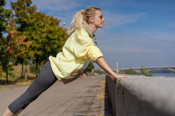 close up on the street on the river embankment in the city center on a concrete path a sporty girl in yellow sports suit healthy lifestyle warm-up imperfect figure