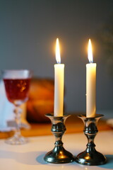 vertical photo Traditional challah bread with wine and glowing candles on dark background. Shabbat Shalom