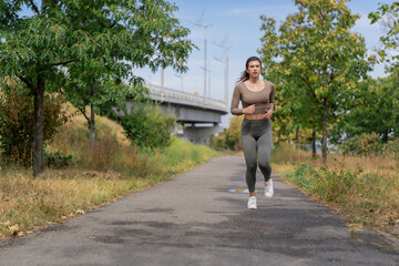 on the street on the river embankment in the city center on  concrete path a sporty girl in a gray sports suit healthy lifestyle morning jogging imperfect figure