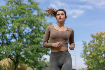 close up on the street on the river embankment in the city center on  concrete path a sporty girl in a gray sports suit healthy lifestyle morning jogging imperfect figure