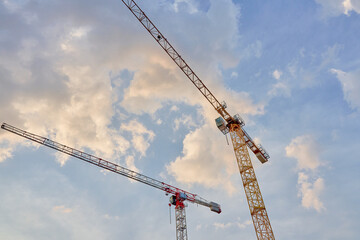 Construction cranes against blue sky. Construction of new housing and development of urban infrastructure