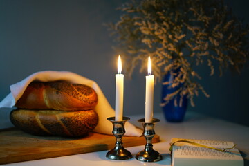 Traditional challah bread with wine and glowing candles on dark background. Shabbat Shalom