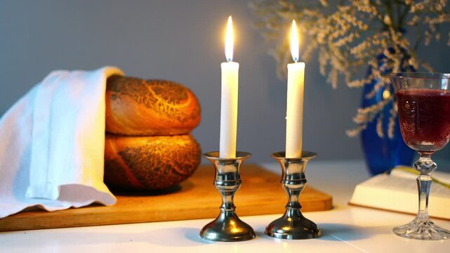 Traditional challah bread with wine and glowing candles on dark background. Shabbat Shalom