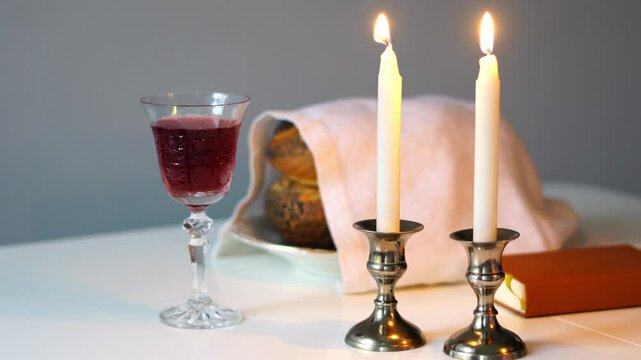 Traditional challah bread with wine and glowing candles on dark background. Shabbat Shalom