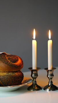 Traditional challah bread with wine and glowing candles on dark background. Shabbat Shalom