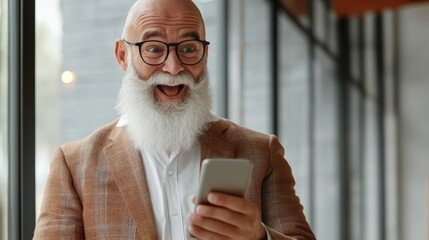 Happy senior bald stylish manager with white beard in a happy surprised expression shile reading news on his smartphone