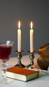 Shabbat or Sabbath kiddush ceremony composition with a traditional sweet fresh loaf of challah bread, glass of red kosher wine and candles on a vintage wood table with copy space