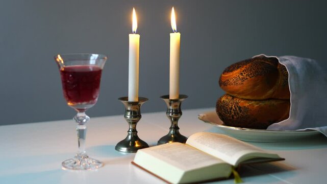 Shabbat or Sabbath kiddush ceremony composition with a traditional sweet fresh loaf of challah bread, glass of red kosher wine and candles on a vintage wood table with copy space