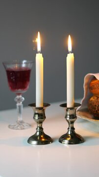 Shabbat or Sabbath kiddush ceremony composition with a traditional sweet fresh loaf of challah bread, glass of red kosher wine and candles on a vintage wood table with copy space