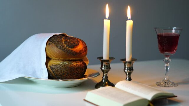 Shabbat or Sabbath kiddush ceremony composition with a traditional sweet fresh loaf of challah bread, glass of red kosher wine and candles on a vintage wood table with copy space