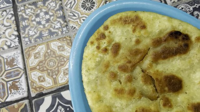 Close-up of a traditional huarache served on a blue plate against patterned vintage tiles