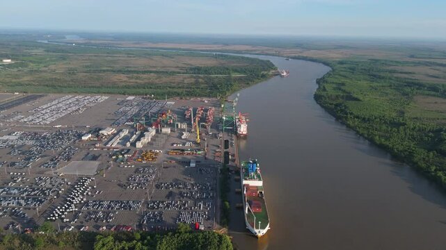 Aerial view of commercial vehicle import port with cargo ships on Paran&aacute; River. Zarate, Buenos Aires, Argentina.