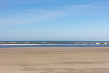Autumn landscape view of wide and long white sand beach under blue sky and white clouds, The Dutch...