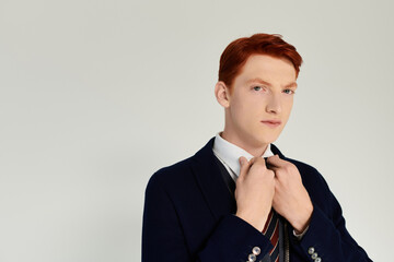 A young man in a layered winter outfit adjusts his tie, embodying sophistication and style in a...