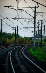 Railway road at autumn evening with autumn colors.Railroad near the forest with powerlines over the trees.Clouds in the sky,photography in the rainy weather .Landscape photo with train on the rails