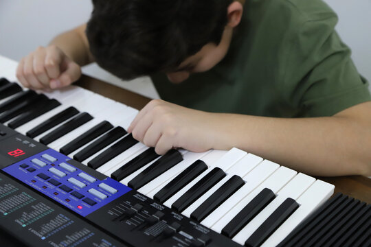 
Angry boy with his electric keyboard classes. Preteen frustrated with his music lesson. Concept of excessive homework and studies.