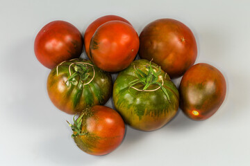 Different ripe green-brown tomatoes kumato on a gray background
