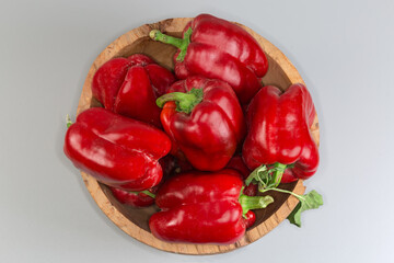 Fresh red bell peppers in vintage wooden bowl, top view