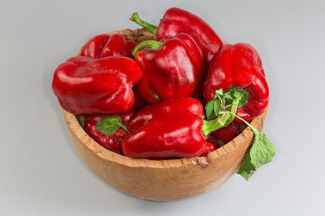 Whole fresh red bell peppers in the vintage wooden bowl