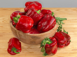Fresh red bell peppers in wooden bowl on rustic table