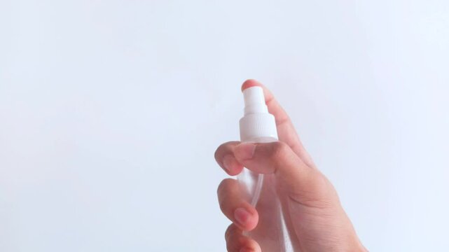 Man's hand spraying perfume bottle on white background, elegant fragrance, advertising purpose.