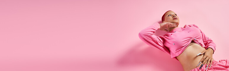 This confident young woman showcases her unique fashion sense in a stylish studio with pink accents.