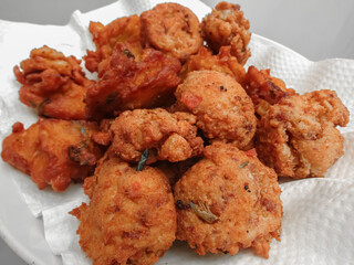 Delicious Indonesian Corn Fritters Dadar Jagung Golden Brown Crisp Fried Snack Served on White Plate with Paper Napkin Minimal Background Perfectly Cooked Traditional Street Food Appetizing Texture