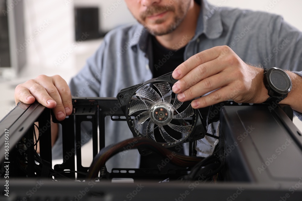 Poster man installing fan into computer at table, closeup