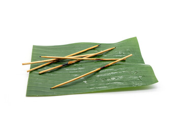 Leftover skewers on the banana leaf of Grilled pork sticks isolated on white background.