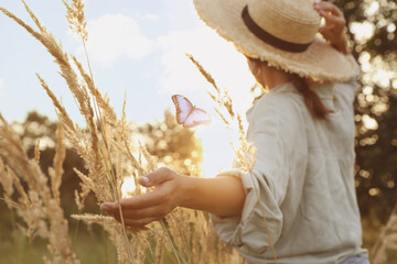 Woman and butterfly in field at sunrise. Health, spring, freedom, beauty