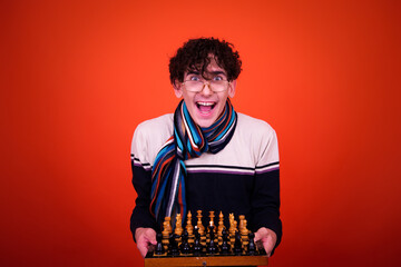 A funny young attractive guy with a curly hairstyle poses in the studio.