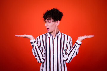 A funny young attractive guy with a curly hairstyle poses in the studio.