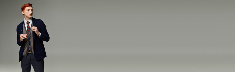 A student with striking red hair presents a sophisticated layered winter ensemble and tie.