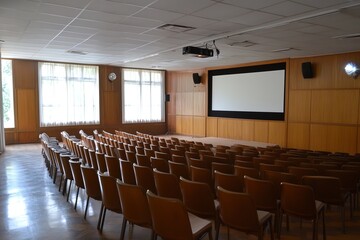 Empty Conference Hall With Rows of Chairs and a Large Screen in a Well-Lit Space During a Daytime Setting