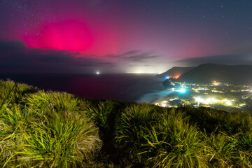 Pink aurora australis view from grassy hill, Sydney, Australia.
