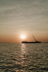 Silhouette of Small Boat Floating at Sunrise with Orange Sky Radiating Morning Peace and Beauty