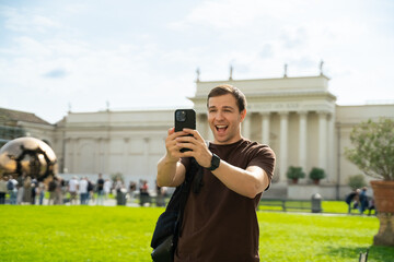 Handsome young stylish man talking in video chat via cell phone speak with friends by video call