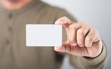 Thai man holds a blank white name card, symbolizing new opportunities and personal branding in a professional setting