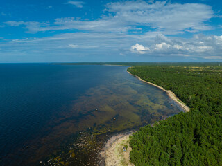 Obraz premium Aerial view of calm and wild Turisalu beach with a clear white sand and brown water (Estonian - Türisalu rand) on a sunny summer day. Big rocks in a calm and brown Baltic sea. 