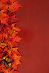Fall leaves and acorns on red wood autumn background