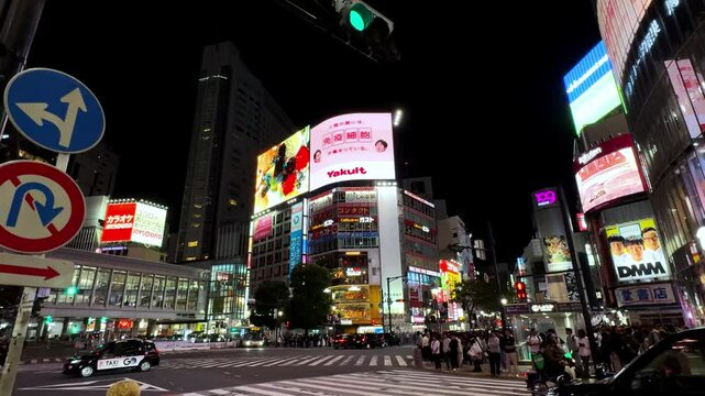 Bustling Shibuya crossing in Tokyo at night with bright neon signs and crowds of pedestrians
