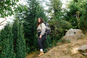 A confident woman enjoys a peaceful stroll through a vibrant natural landscape, surrounded by trees.