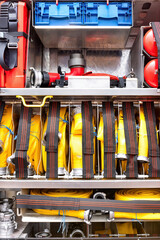 Organized firefighter gear in truck compartment, hoses, nozzles, emergency equipment in firetruck storage space, rescue readiness concept