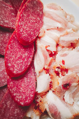 Sliced smoked sausage and bacon pieces. Close-up, selective focus. Vertical photo.